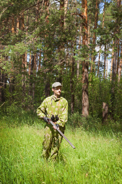 istock Hunter dressed in camouflage and with shotgun is walking through forest 1219010197