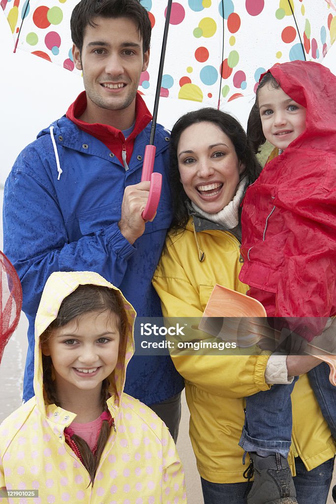 Familia feliz en la playa con sombrilla - Foto de stock de 20 a 29 años libre de derechos