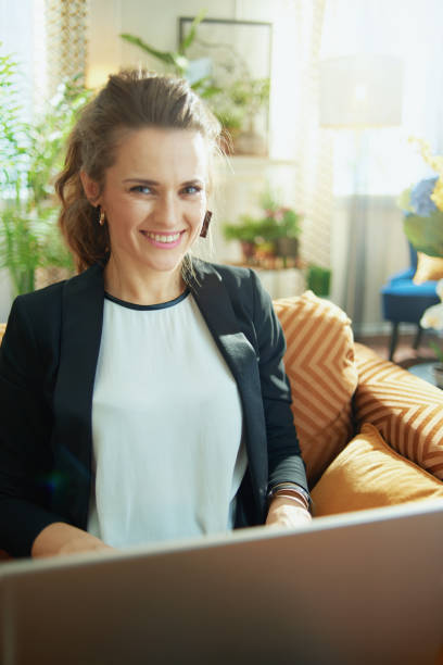 istock happy stylish woman reading text while sitting on sofa 1219011924