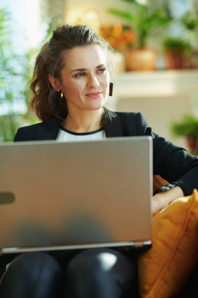 istock pensive stylish woman editing on laptop while sitting on couch 1219011925