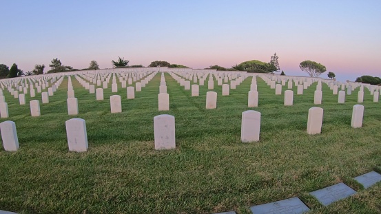 San Diego, California, United States - July 31, 2018: Cemetery graveyard white tombstones at evening. American war cemetery in Point Loma of San Diego, California. Rows of gravestones by the ocean.