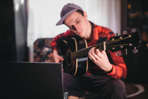 istock A man playing guitar next to a laptop 1219012422