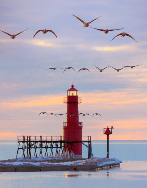 Iconic Lighthouse in icy cold harbor, silhouetted against dawn sky.