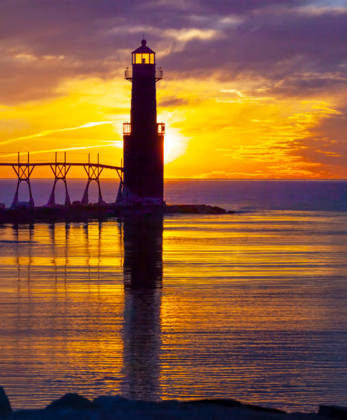 Iconic Lighthouse in icy cold harbor, silhouetted against dawn sky.