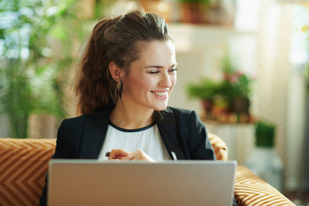 istock happy stylish female using laptop while sitting on sofa 1219015869