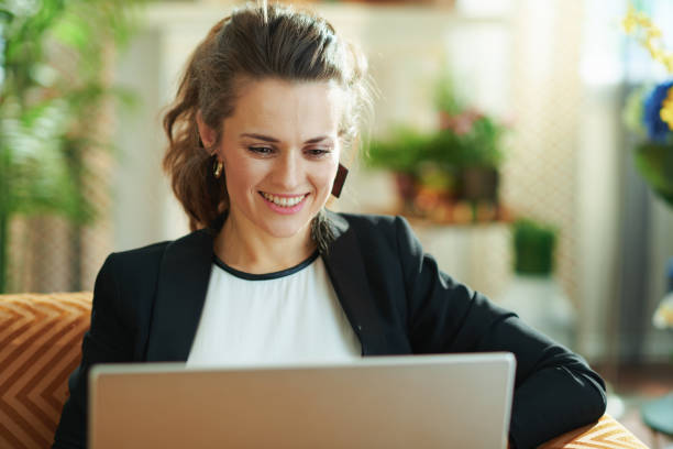 happy trendy woman doing research while sitting on sofa