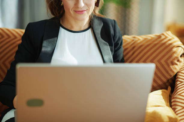 istock stylish housewife writing on laptop while sitting on couch 1219017601