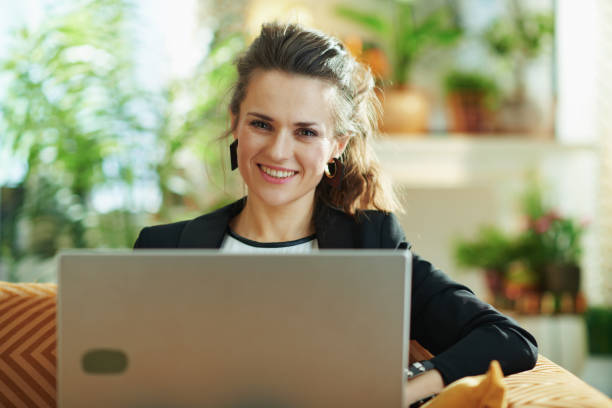 istock smiling stylish woman editing while sitting on divan 1219017602