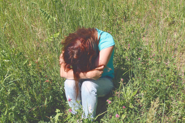 istock Sad lonely girl is sitting on the grass. 1219020366