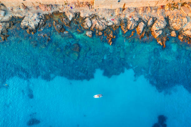 vue aérienne de la plage avec des pierres et des roches, bateau seul dans la mer adriatique au coucher du soleil en été. vue supérieure du yacht dans l’eau bleue transparente. voyage en croatie. fond de nature. paysage avec l’océan - morning croatia blue sea photos et images de collection