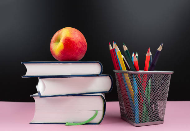 education concept, fresh apple on stack of books next to pencil cup