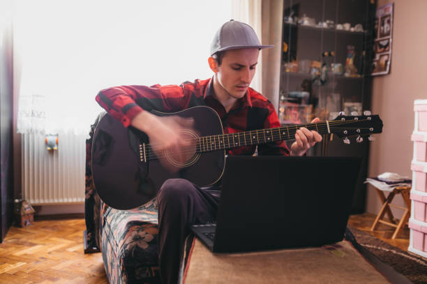 istock A man playing guitar next to a laptop 1219025398