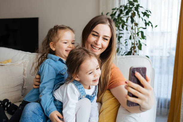 istock Cheerful mother holding smartphone making selfie with daughters 1219025668