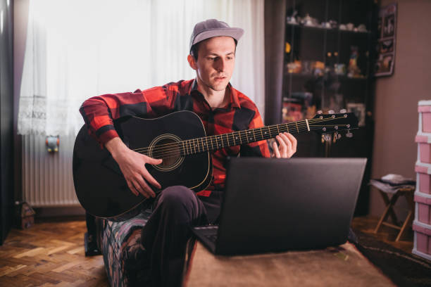 istock A man playing guitar next to a laptop 1219026269