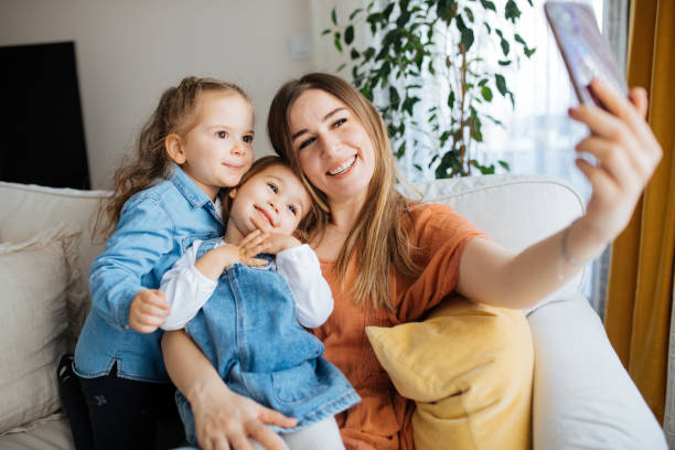 istock Cheerful mother holding smartphone making selfie with daughters 1219026519