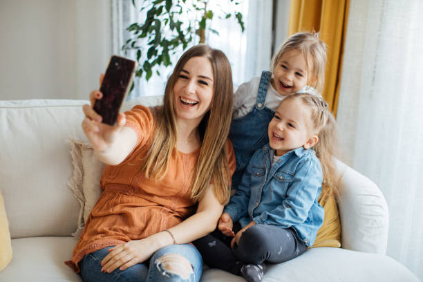 istock Cheerful mother holding smartphone making selfie with daughters 1219026579