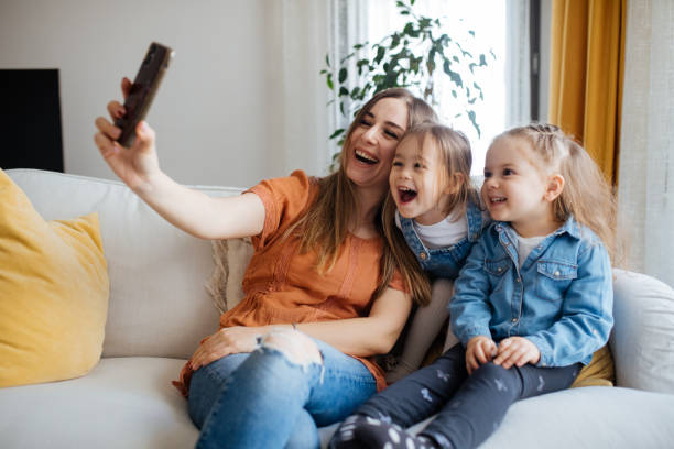 istock Cheerful mother holding smartphone making selfie with daughters 1219026695