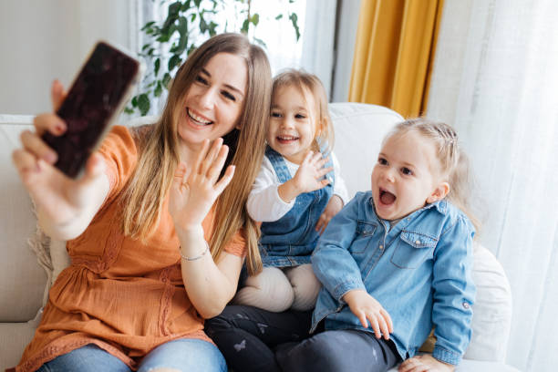 istock Cheerful mother holding smartphone making selfie with daughters 1219027142