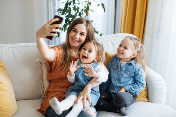 istock Cheerful mother holding smartphone making selfie with daughters 1219028415