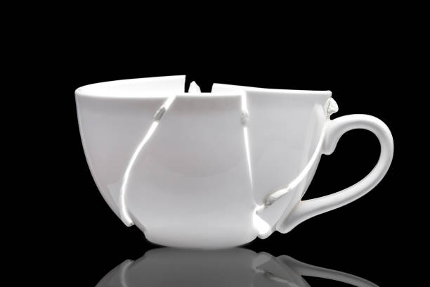 istock white ceramic cup broken into fragments as a result of the fall and glued together chewing gum in the hope of solving the problem, a concept on the theme of crisis and collapse on a black background. 1219028765