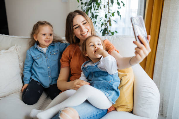 istock Cheerful mother holding smartphone making selfie with daughters 1219028858