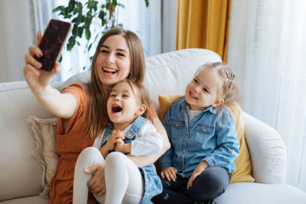 istock Cheerful mother holding smartphone making selfie with daughters 1219028900