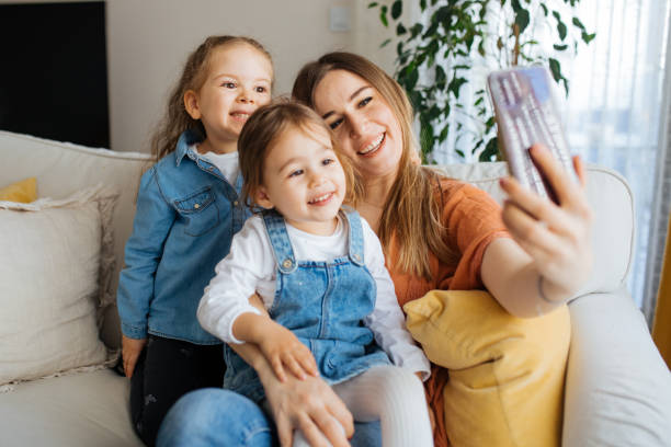 istock Cheerful mother holding smartphone making selfie with daughters 1219029471