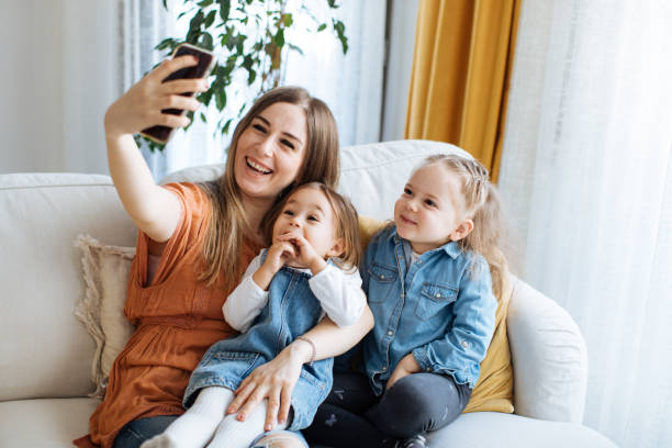 istock Cheerful mother holding smartphone making selfie with daughters 1219029644