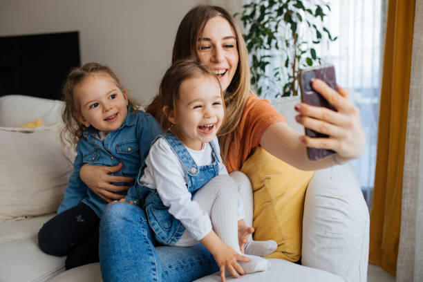 istock Cheerful mother holding smartphone making selfie with daughters 1219029767