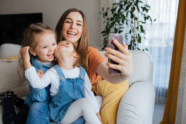 istock Cheerful mother holding smartphone making selfie with daughters 1219029931