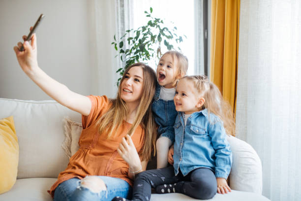istock Cheerful mother holding smartphone making selfie with daughters 1219030803