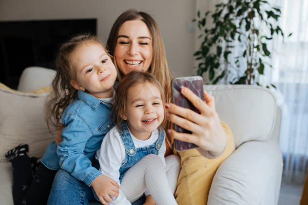 istock Cheerful mother holding smartphone making selfie with daughters 1219030881