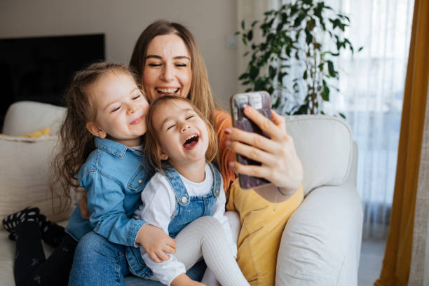 istock Cheerful mother holding smartphone making selfie with daughters 1219031072
