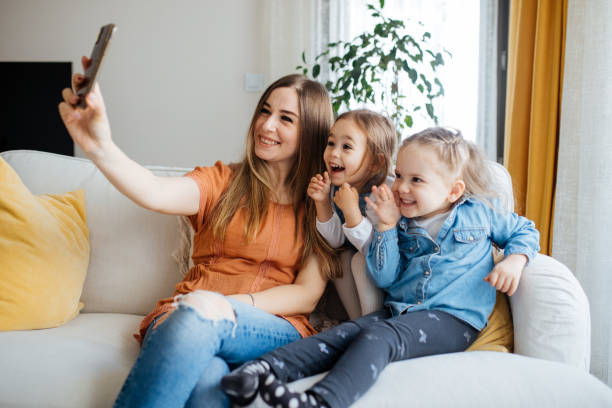 istock Cheerful mother holding smartphone making selfie with daughters 1219031150