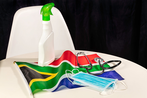 Protection from viruses in South Africa, with doctors' Stethoscope, face masks, hand sanitizer spray bottle and south african flag, allowing for copy space.