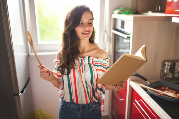 Woman reading cookbook and cooking