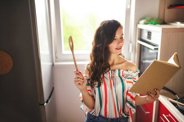 istock Woman reading cookbook and cooking 1219032092