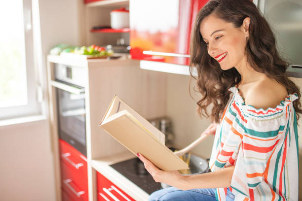 istock Beautiful woman cooking and reading cookbook 1219034240
