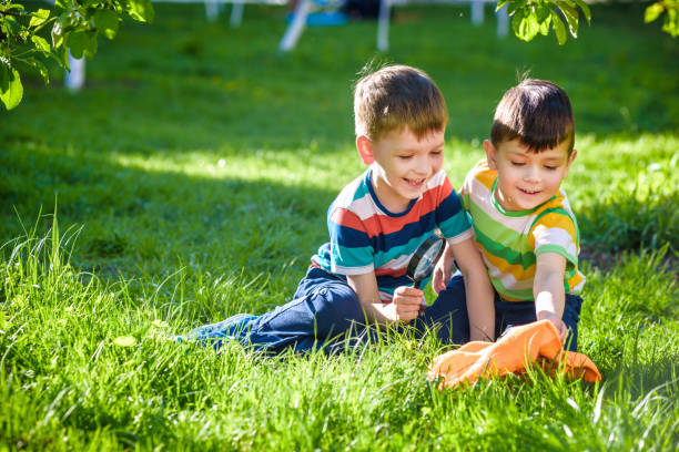 istock Adorable kid boy making fire on paper with a magnifying glass outdoors, on sunny day. 1219035378