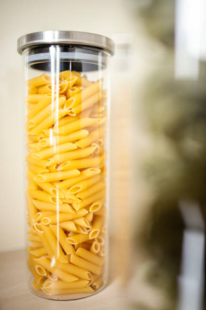 Close-up of uncooked pasta items in airtight jars