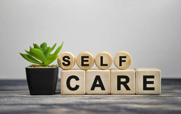 self care - text auf holzwürfeln, grüne pflanze im schwarzen topf auf holzhintergrund - wellness stock-fotos und bilder