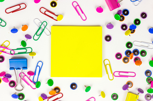 Bright pink, yellow, blue and green stationery accessories for office and education on white background with sticky notes copy space.