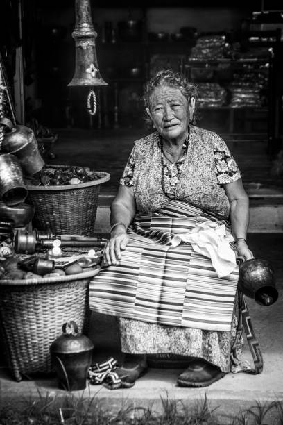 Tibetan store Pokhara, Nepal- September 3 2017: Portrait in black and white of an old tibetan woman in her craft store at the tibetan refugee camp named Tashiling, in Pokhara, Nepal. prayer wheel nepal kathmandu buddhism stock pictures, royalty-free photos & images