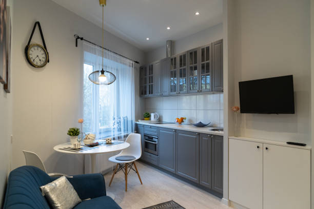 Interior of a studio apartment, kitchen Stylish cozy kitchen interior design in the modern studio apartment. Kitchen furniture by the window and a rest area with a sofa and a TV confined space stock pictures, royalty-free photos & images