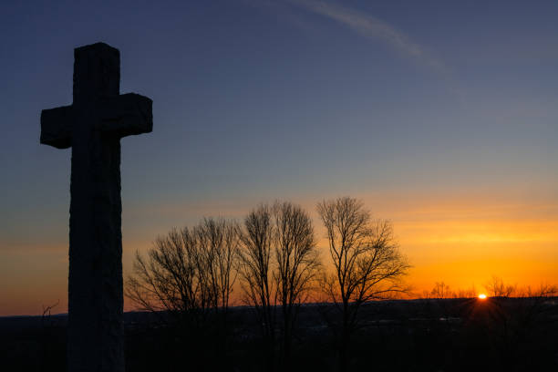 A cemetery filled with crosses. The sun represents God or light overhead a statue of Jesus.