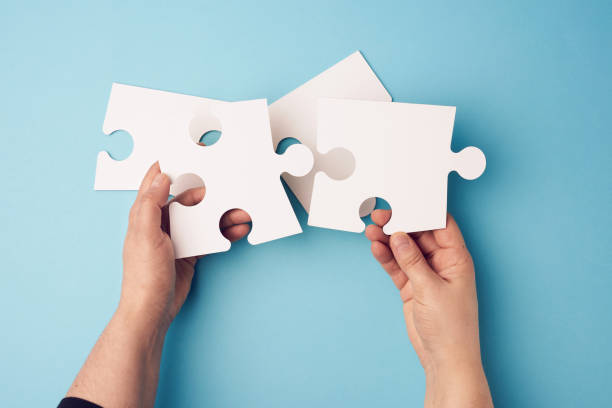 two female hands holding big paper white blank puzzles on a blue background