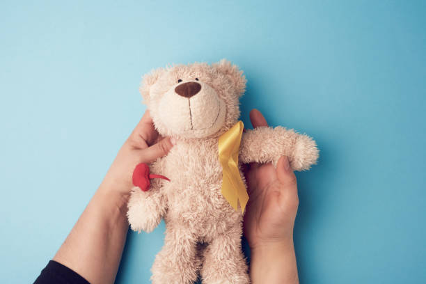 istock female hands hold a small teddy bear with a yellow ribbon folded in a loop 1219049267