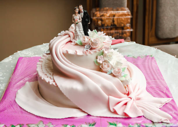 istock Two-tier white wedding cake with a mastic and bridegroom figurine as decoration. Wedding concept. 1219050119