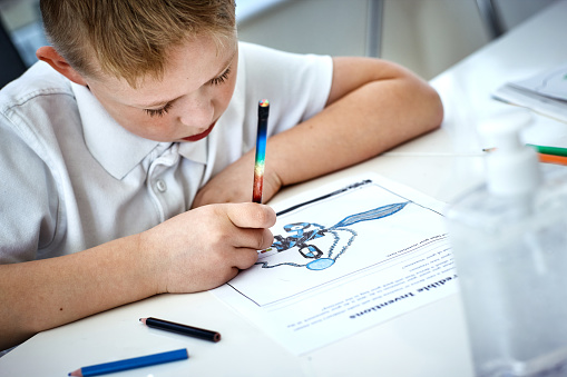 Cropped shot of an adorable little boy drawing and doing his homework at home