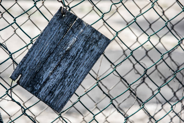 istock Old cracked rectangular wooden plate on an old green mesh fence 1219051571